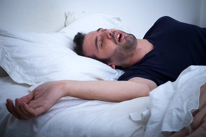 Man snoring in his bed needs help from Star Image Dentistry in Wichita Falls, Texas