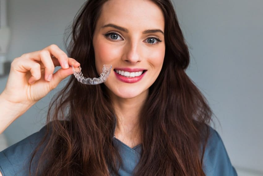 young adult woman holding an invisalign